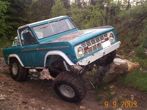 1977 Ford Bronco - This 1977 Ford Bronco is navigating a challenging off-road course with large rocks and mud.