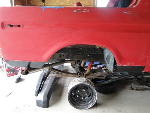 1978 Ford Bronco - A red vehicle's rear quarter panel and suspension are visible, undergoing restoration work.