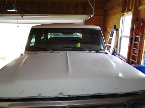 1978 Ford Bronco - Front view of a white SUV, possibly undergoing restoration, parked inside a garage.
