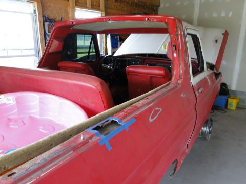 1978 Ford Bronco - Interior view of a red pickup truck undergoing restoration, with a pink inflatable pool in the bed.