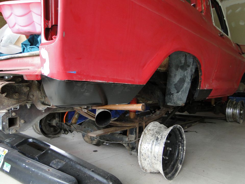 Red 1978 Ford Bronco rear axle with leaf springs, exhaust pipe, and a detached wheel