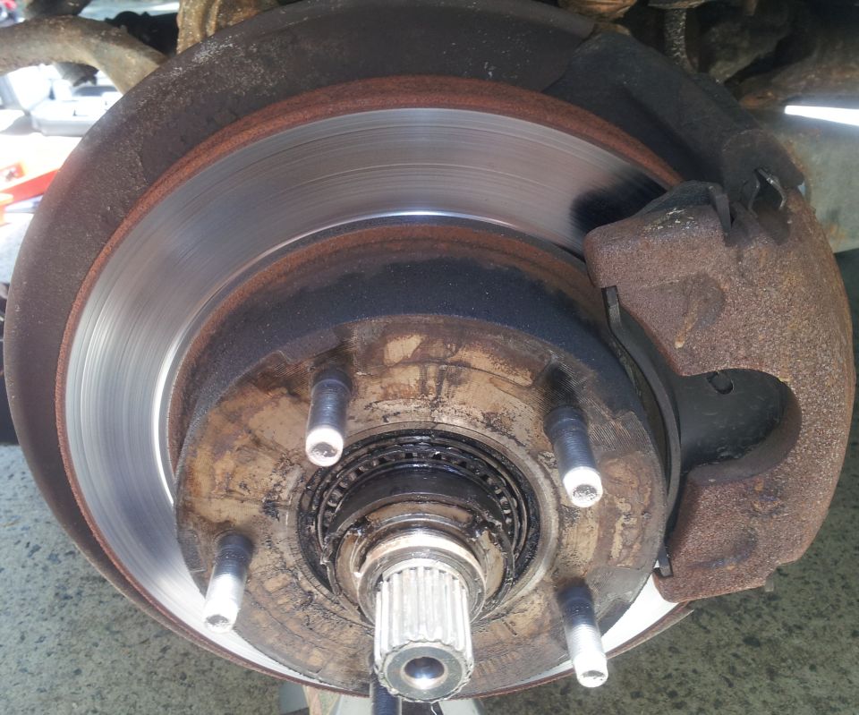 Brake rotor and hub with wheel removed, rusty caliper mounted at right