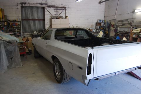 1975 Ford Ranchero - A white Ford Ranchero is parked inside a workshop, appearing to be undergoing repairs or restoration.