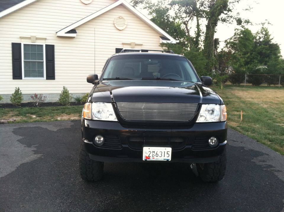 Black Ford Explorer SUV with aftermarket grille, parked in driveway