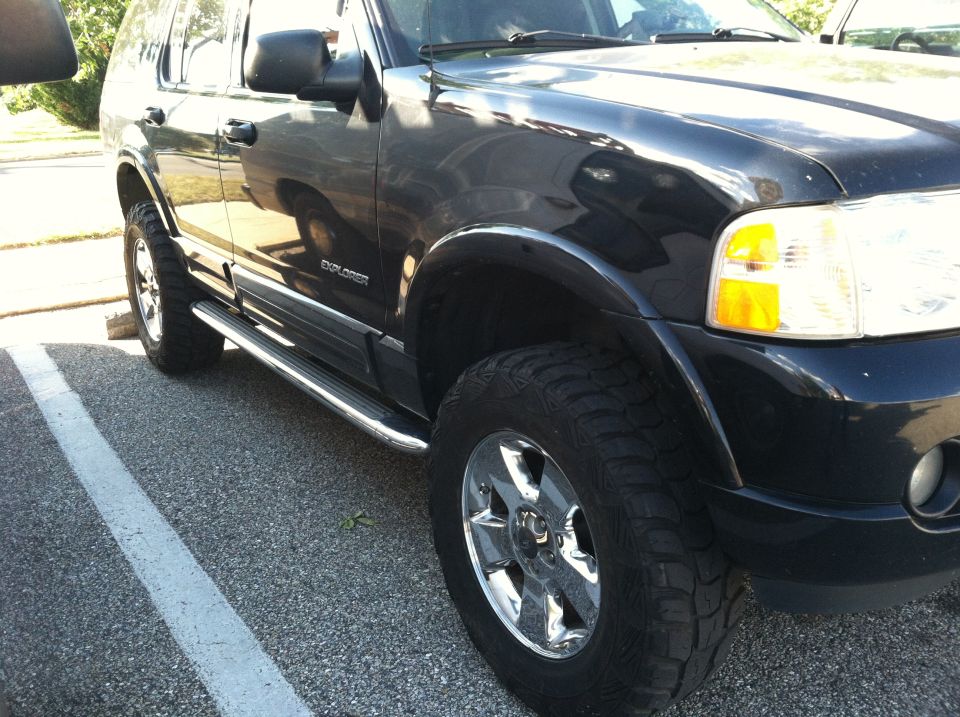 Dark 2005 Ford Explorer 3/4 front view with chrome side steps and aftermarket wheels