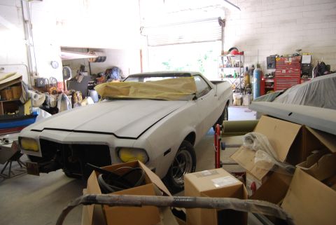 1975 Ford Ranchero - A 1975 Ford Ranchero is being worked on in a garage, with another vehicle covered in the background.