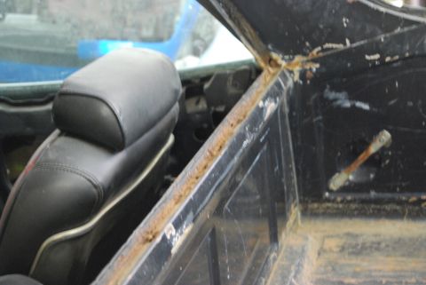 1975 Ford Ranchero - Close-up of the interior of a vehicle, highlighting a black seat and significant rust on the metal trim.