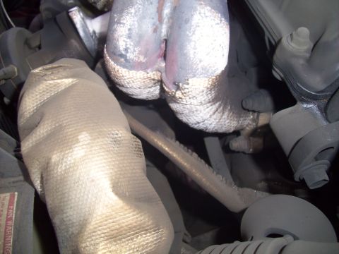 1995 Ford Probe - The image shows a close-up view of a vehicle's exhaust manifold, partially covered with heat-resistant wrap.