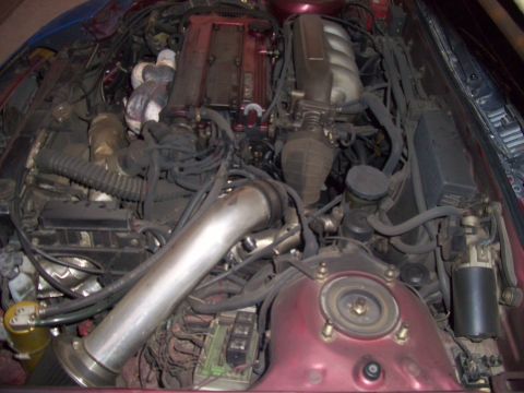 1995 Ford Probe - The engine bay of a vehicle is shown, a complex arrangement of mechanical parts and wiring.