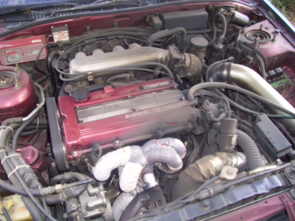 Engine bay with a red Mazda DOHC 16-valve engine, MSD ignition box, and custom exhaust manifold