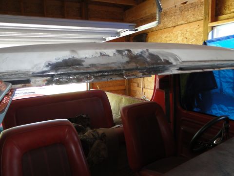 1978 Ford Bronco - The interior of a red Bronco shows seats and the steering wheel, with work being done on the roof.