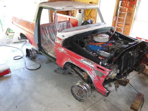 1978 Ford Bronco - This red and white pickup truck is undergoing restoration, with its engine visible and wheels removed.