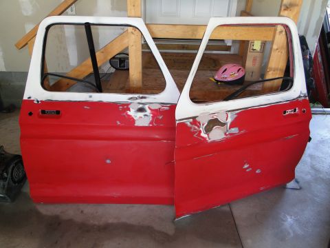 1978 Ford Bronco - Two red and white car doors, showing signs of repair and body filler, are displayed indoors.