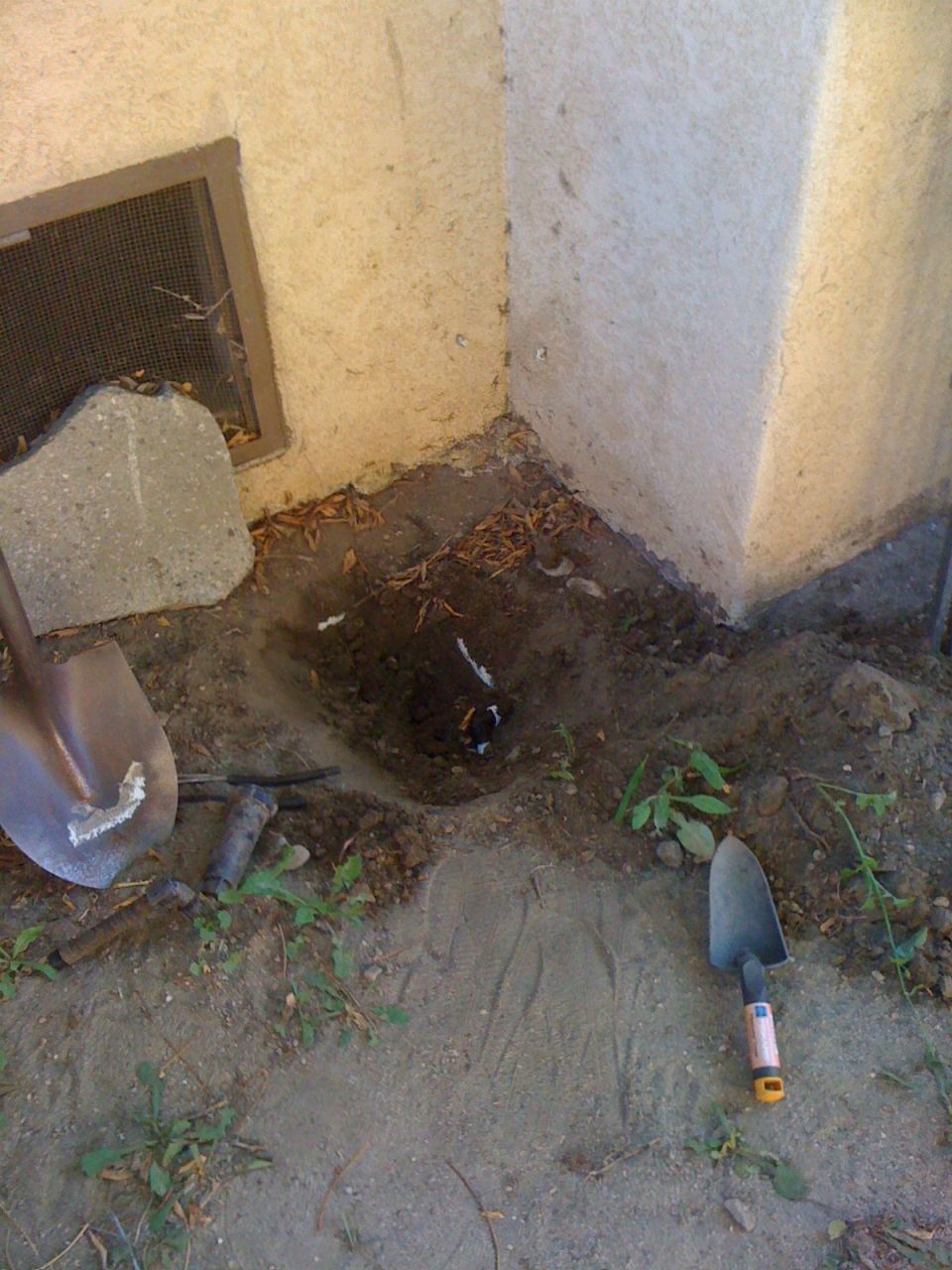 Excavation site with shovels, pipes, and disturbed earth