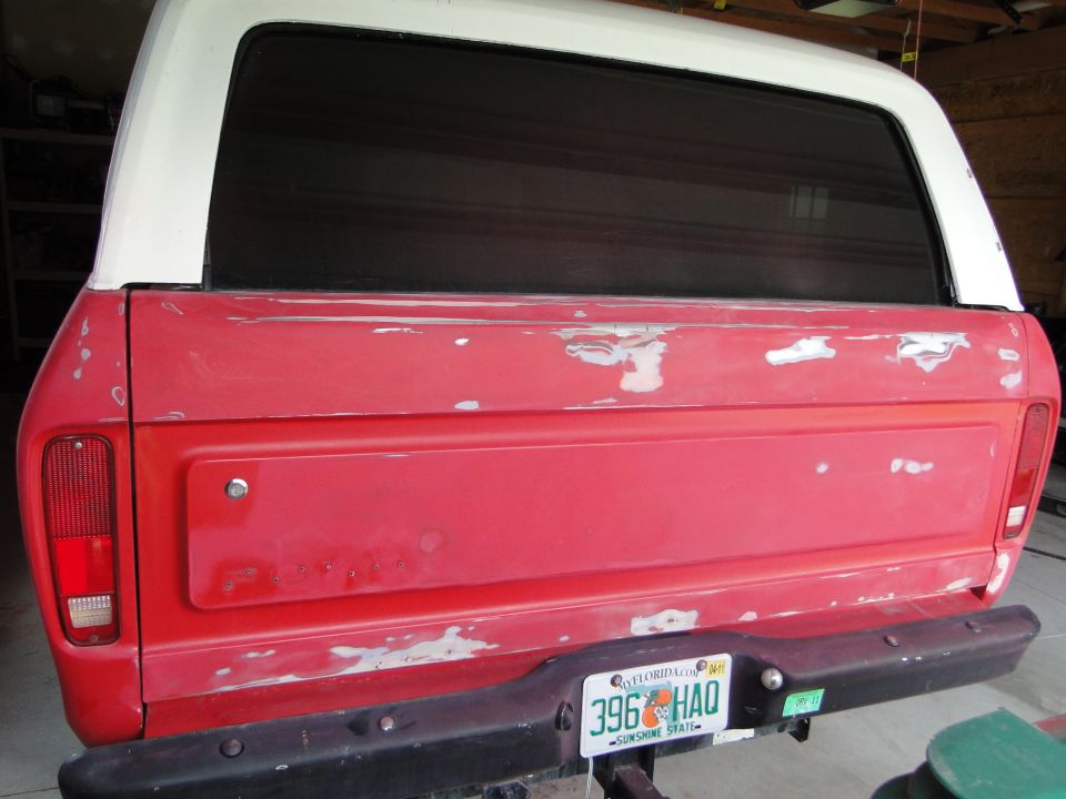 Rear of a red 1978 Ford Bronco with a white top, showing primer spots and a Florida license plate