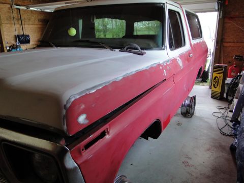 1978 Ford Bronco - This 1978 Ford Bronco is undergoing bodywork in a garage, with its hood prepped for paint and one wheel off.