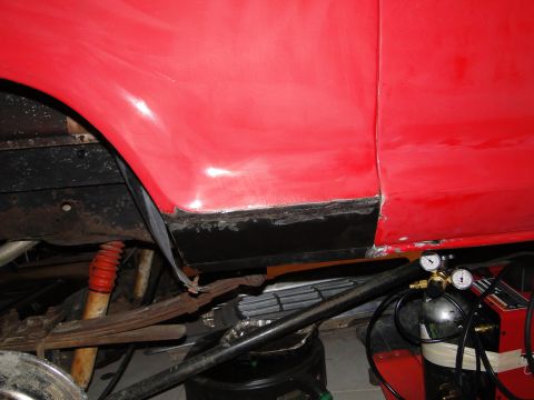 1978 Ford Bronco - Undercarriage view of a vehicle undergoing repair, showing suspension components and welding equipment.