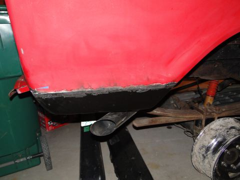 1978 Ford Bronco - Close-up of a red vehicle's undercarriage shows exposed metal and an exhaust pipe.