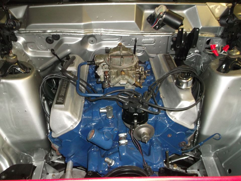 Blue Ford V8 with four-barrel carb and Cyclone GT valve covers in a bare-metal engine bay