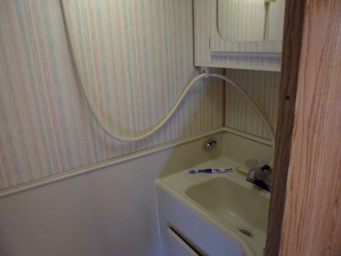 1991 Ford Bronco - Interior view of a small RV bathroom sink area with a shower head hose.