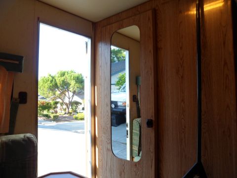1991 Ford Bronco - The interior of a vehicle shows a mirror reflecting a white SUV parked outside.