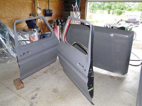 1978 Ford Bronco - Car doors and hood are disassembled in a garage, awaiting restoration or repair.