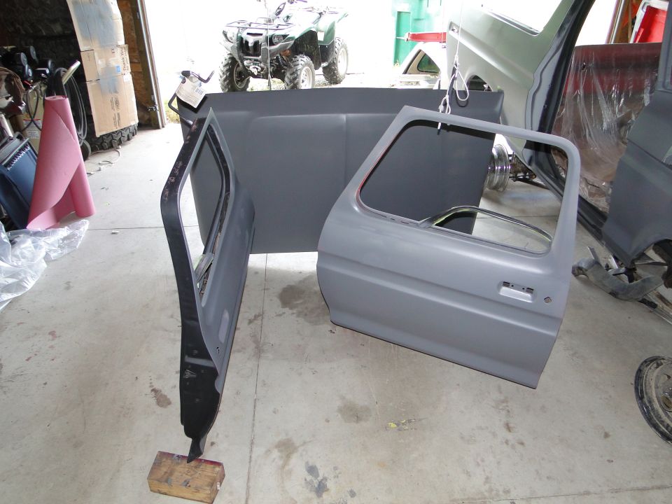 Gray vehicle doors and bed panel disassembled in garage. ATV in background