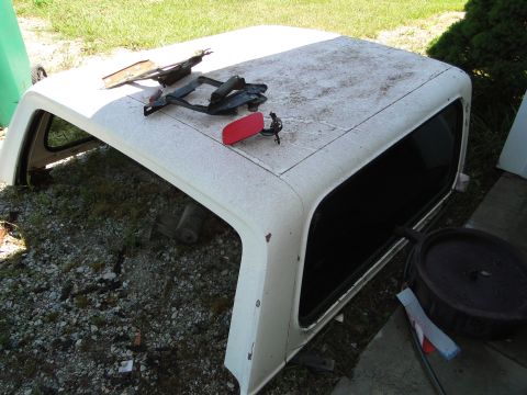 1978 Ford Bronco - A detached hardtop for a Ford Bronco is shown outdoors, resting on the ground.