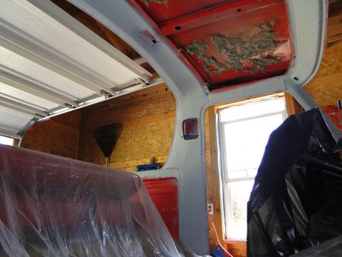 1978 Ford Bronco - The interior of a 1978 Ford Bronco shows exposed insulation and red seats covered in protective plastic.