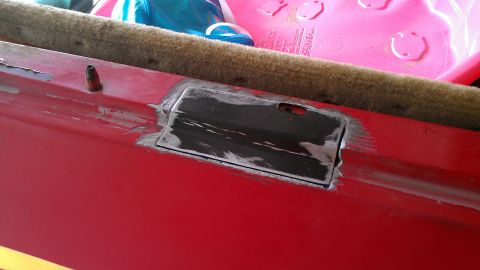 1978 Ford Bronco - Close-up of a red vehicle's interior, showing a metal plate and a small post.