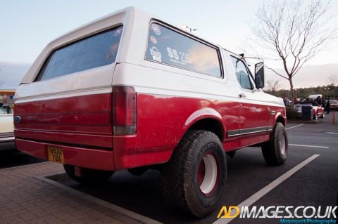 1989 Ford Bronco - This two-tone Ford Bronco is parked in a lot with other vehicles visible in the background.
