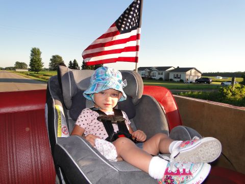 1978 Ford Bronco - Child rides in a car seat with an American flag waving behind them.