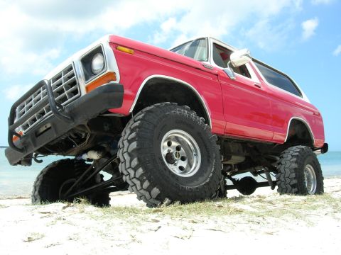 1978 Ford Bronco - This red 1978 Ford Bronco is parked on a beach with a clear blue sky overhead.
