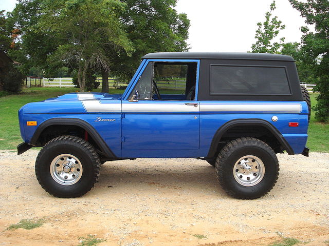 Blue 1978 Ford Bronco with silver stripe and black hardtop, seen from the side