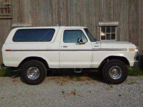 1978 Ford Bronco - A white 1978 Ford Bronco is viewed from the side, parked in front of a rustic wooden barn.