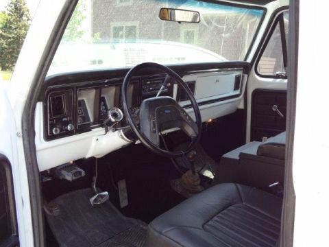 1978 Ford Bronco - The interior of a 1978 Ford Bronco features a white dashboard and black leather seats.