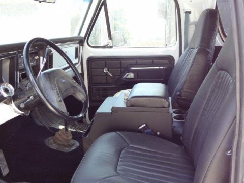1978 Ford Bronco - The interior of a 1978 Ford Bronco features black vinyl seats and a dark dashboard with a large steering wheel.