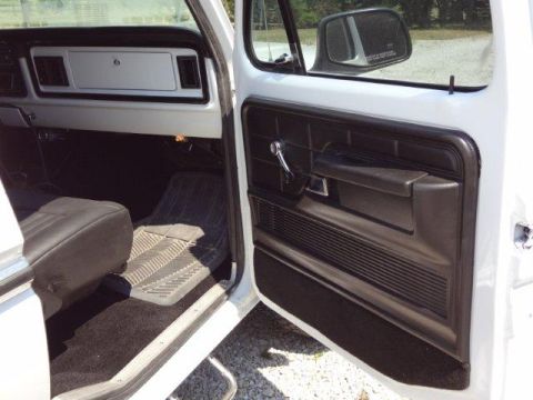 1978 Ford Bronco - Interior view of a white truck, revealing the driver's side door panel and seat.