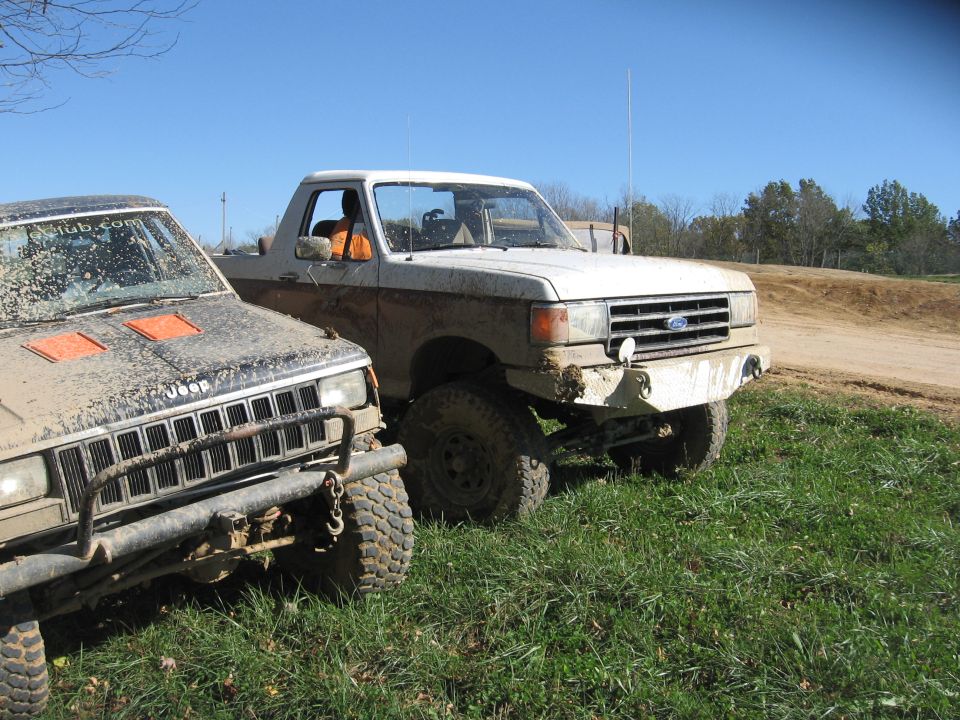 Muddy Ford Bronco II parked next to a Jeep Cherokee. Both are off-road vehicles