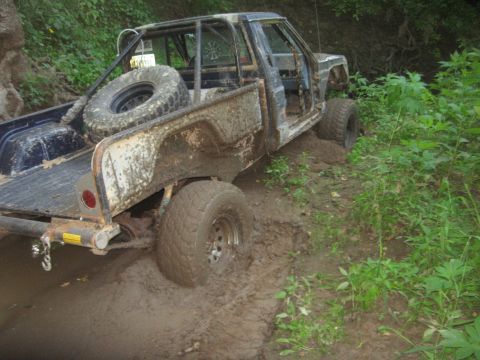 1987 Jeep Comanche - Muddy 1987 Jeep Comanche with roll cage stuck in off-road terrain.