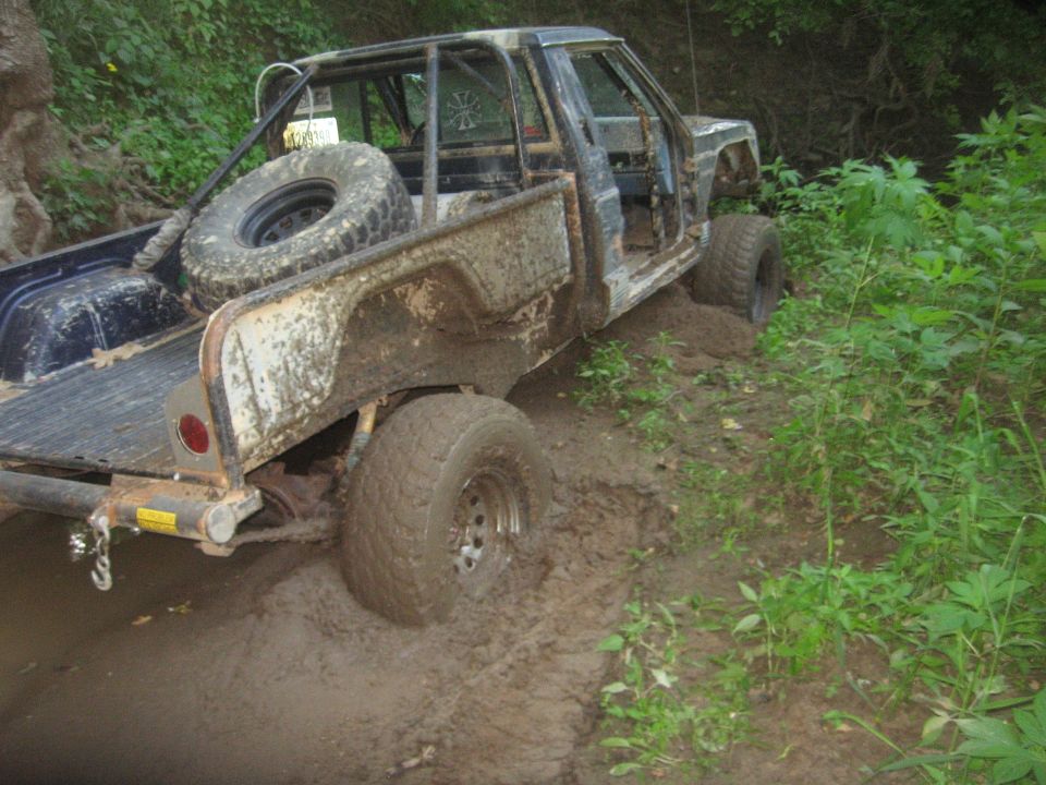 1987 Jeep Comanche modified for off-roading, stuck in mud with roll cage and spare tire