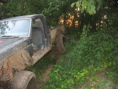 1987 Jeep Comanche - This 1987 Jeep Comanche is seen in a wooded area, with its door open and tires covered in mud.