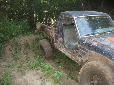 1987 Jeep Comanche - Mud-covered 1987 Jeep Comanche pickup truck seen off-road with "ComancheClub.com" on windshield.