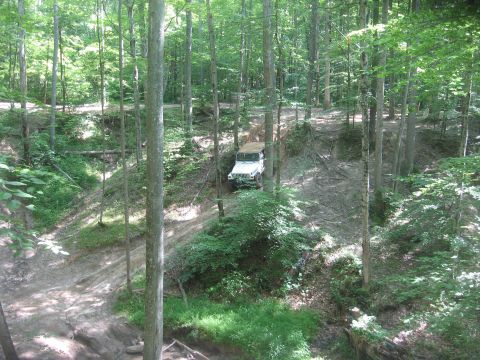1987 Jeep Comanche - A white 1987 Jeep Comanche navigates a wooded trail, kicking up dust.