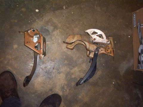 1991 Ford LTD Crown Victoria - Two vehicle pedal assemblies are shown on a concrete floor, with a U-Haul box in the background.