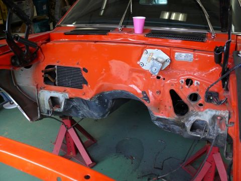 1968 Chevrolet Camaro - The engine bay of a car is shown with orange paint, missing its engine and supported by jack stands.