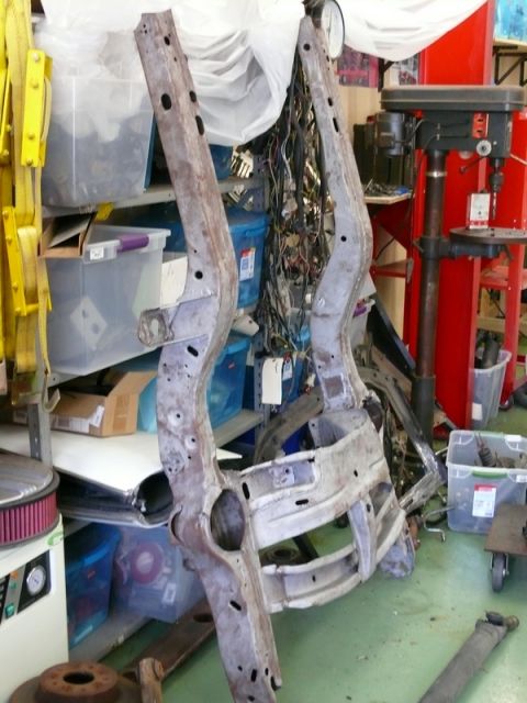 1968 Chevrolet Camaro - Two sections of a car frame are suspended, surrounded by workshop clutter and storage bins.