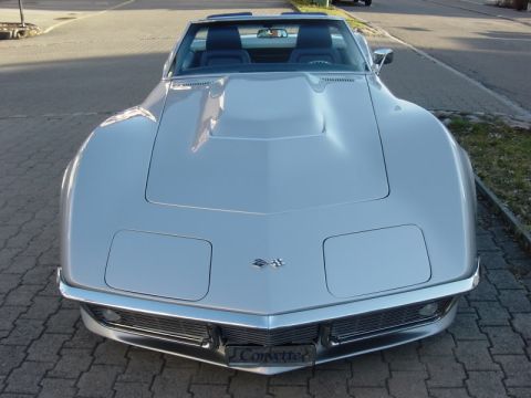 1976 Chevrolet Corvette - This silver convertible features a prominent hood scoop and a classic chrome grille, with a "Corvette" badge visible on the front.