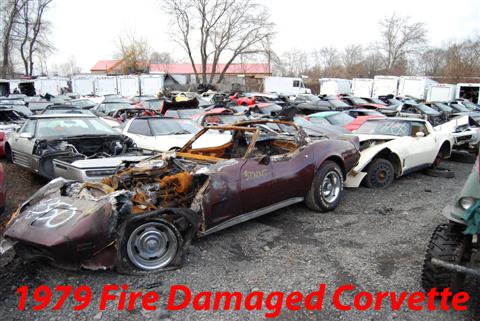 1976 Chevrolet Corvette - This heavily damaged 1979 Corvette sits in a junkyard, surrounded by other vehicles.