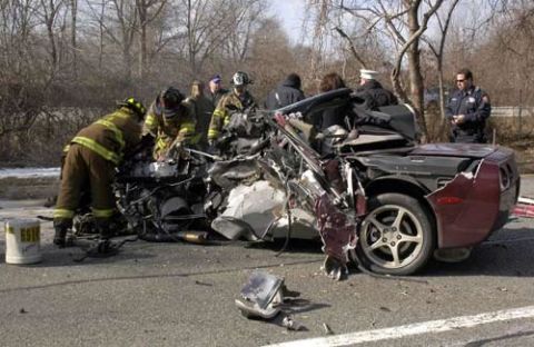 1976 Chevrolet Corvette - A severely damaged red Corvette is attended to by emergency personnel, with police officers observing the scene.